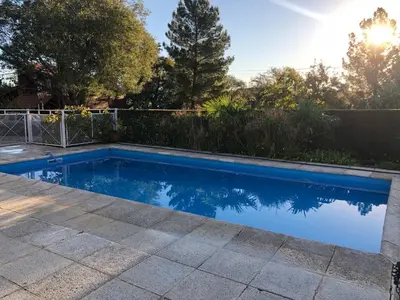 a swimming pool in a yard with a fence and trees at Cabaña Los Estribos 1 in Merlo