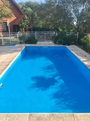 a blue swimming pool with a shadow of a palm tree at Cabaña Los Estribos 1 in Merlo
