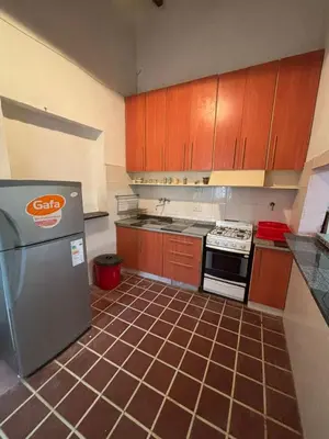a kitchen with wooden cabinets and a tile floor at Refugio de Nestor in Villa Parque Siquiman