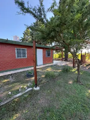 a fence in front of a house with a tree at Las tres lunas in Villa Anizacate