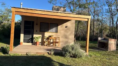 a small house with a porch and a table at Cabaña tranquila y gran parque ideal para parejas in Villa Anizacate