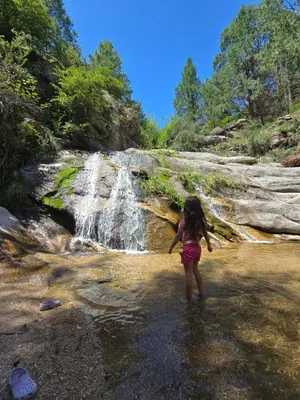a little girl standing in front of a waterfall at Adlerhaus in La Cumbrecita