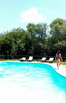 a woman in a bikini walking into a swimming pool at Tinkunaco Merlo in Merlo