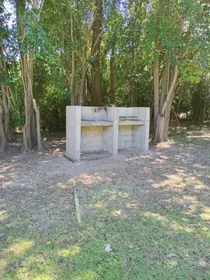 a concrete bench sitting in a park with trees at Tinkunaco Merlo in Merlo