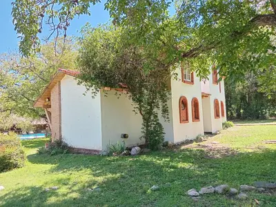 a small white house with a tree in the yard at Tinkunaco Merlo in Merlo