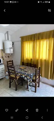 a dining room table with two chairs and a yellow curtain at Elrincondemaximo in Santa Rosa de Calamuchita