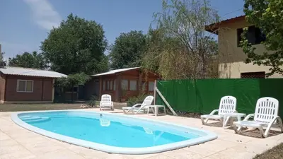 a pool with white chairs and a fence at Aimara Casas de alquiler in Mina Clavero