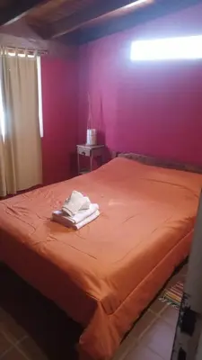 a bedroom with a orange bed with towels on it at Aimara Casas de alquiler in Mina Clavero