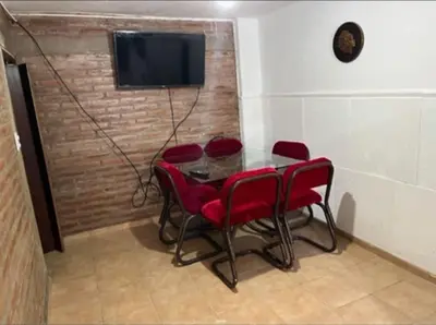 a dining room with a table and red chairs at Casa interna en Playas de Oro Carlos Paz in Villa Carlos Paz