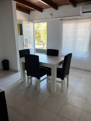 a dining room table with chairs and a window at Complejo Joaquina in Río Cuarto