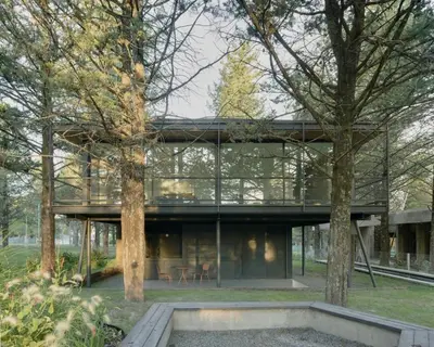 a glass house in a park with trees at Casa entre pinos in La Florida