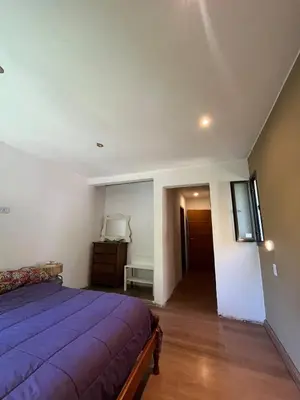 a bedroom with a purple bed and a hallway at casa junto al rio para 7 in Villa Carlos Paz