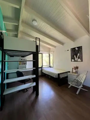 a bedroom with a bunk bed and a couch and a chair at casa junto al rio para 7 in Villa Carlos Paz