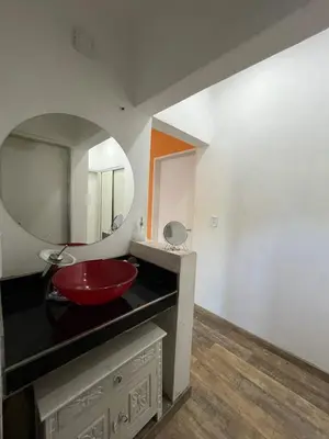 a bathroom with a red sink and a mirror at casa junto al rio para 7 in Villa Carlos Paz