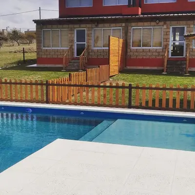 a house with a fence next to a swimming pool at Aires de Montaña cabañas in La Estancia