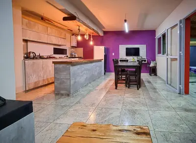 a kitchen with a table and a purple wall at Aires de Montaña cabañas in La Estancia