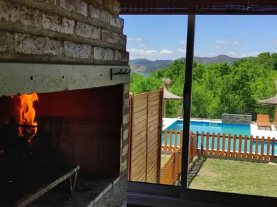 a fireplace in a house with a view of a pool at Aires de Montaña cabañas in La Estancia