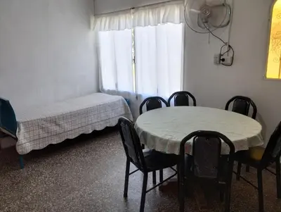 a room with a table and chairs and a bed and a window at Los duraznos in Villa Cura Brochero