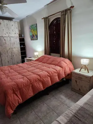 a bedroom with a large bed with a red comforter at Casa Chalet Carlos Paz in Villa Carlos Paz