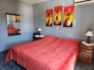 a bedroom with a red bed and paintings on the wall at Casa Chalet Carlos Paz in Villa Carlos Paz