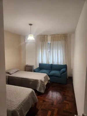 a bedroom with two beds and a blue couch at Departamento con Estilo centro Cordoba - Cañada y Av Colon in Cordoba