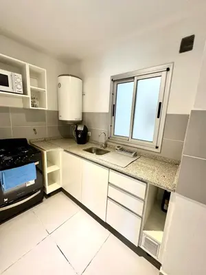 a kitchen with white cabinets and a sink and a window at Departamento Alberdi para 4 personas in Cordoba