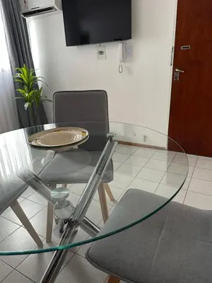 a glass table in a room with a chair and a tv at Apartamento Betania in Cordoba