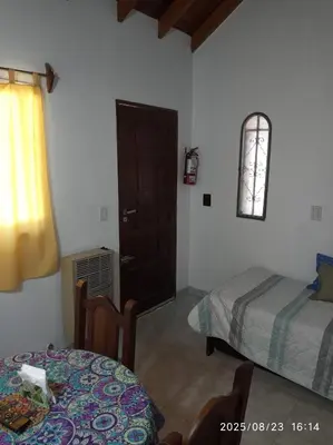 a room with two beds and a table and a window at Los Cachilos in Merlo