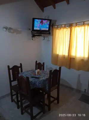 a dining room with a table and a tv on the wall at Los Cachilos in Merlo