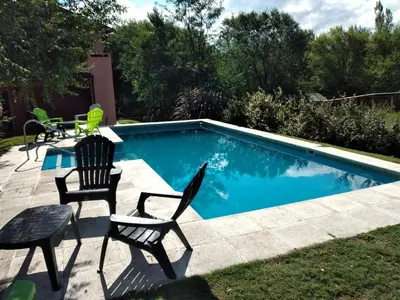 a swimming pool with chairs and a table next to it at Complejo Aguas Calmas - Casa Remanso in Los Reartes