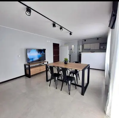 a living room with a table and chairs and a kitchen at Depto Nuevo en el Centro, Cochera, Pile, Aire Ac in Villa Carlos Paz