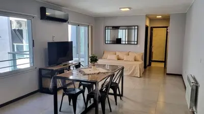 a living room with a couch and a table with chairs at Depto Nuevo en el Centro, Cochera, Pile, Aire Ac in Villa Carlos Paz