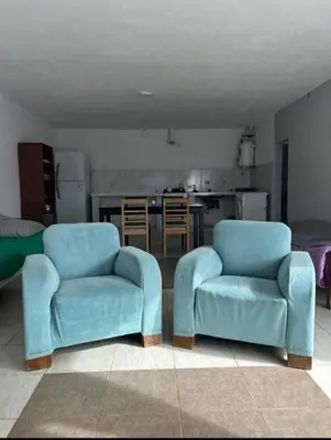 two blue chairs in a living room with a kitchen at Departamento 2 in Río Cuarto