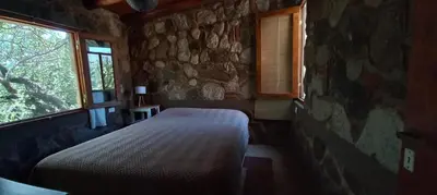 a bedroom with a bed and a stone wall at Casa FUJI in Villa de Las Rosas