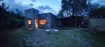 a stone house with two chairs in the yard at Casa FUJI in Villa de Las Rosas
