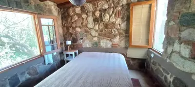 a bedroom with a bed in a stone wall at Casa FUJI in Villa de Las Rosas