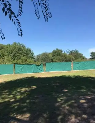 a green fence in a field with trees in the background at Alquiler Temporal vacaciones in Villa Carlos Paz