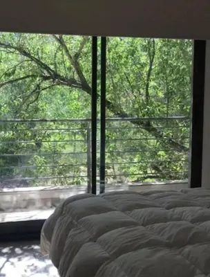 a bedroom with a bed and a large window at Alquiler Temporal vacaciones in Villa Carlos Paz