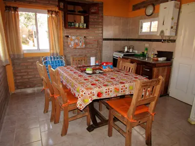 a kitchen with a table with chairs and a table cloth at CABAÑAS SANTA RITA - Tanti, Córdoba in Tanti