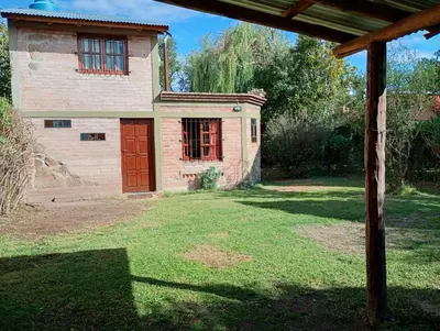 an old house with a red door in a yard at Casita Loma Hermosa in Mina Clavero
