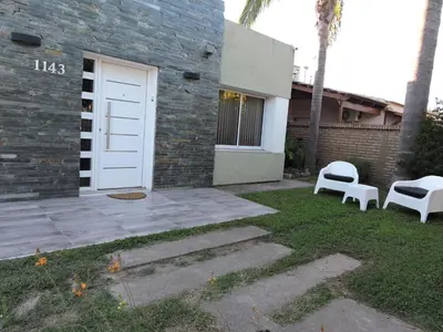 a house with a white door and two white chairs at Algarrobo in Almafuerte