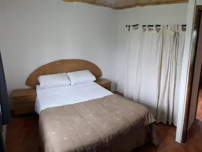 a bedroom with a bed with white sheets and a window at CABAÑAS La Perla in Bialet Massé