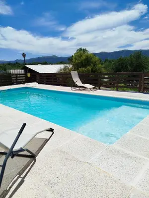 a swimming pool with two lounge chairs next to it at CABAÑAS La Perla in Bialet Massé