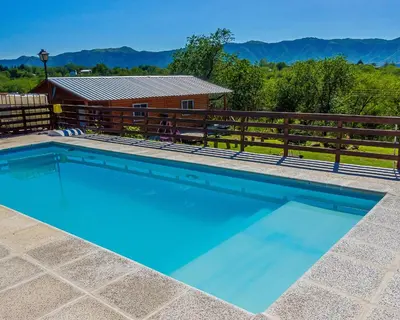 a swimming pool in front of a house with a fence at CABAÑAS La Perla in Bialet Massé