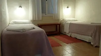 a room with two beds and a table and windows at Las Icarias Casas de campo in Las Calles