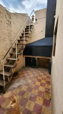 a staircase in an old building with a dog standing in a room at Departamento house in Río Cuarto