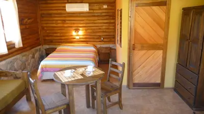 a small room with a bed and a table and a door at Rincón de los Troncos in Merlo
