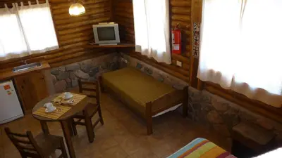 a small room with a bench and a table and a tv at Rincón de los Troncos in Merlo