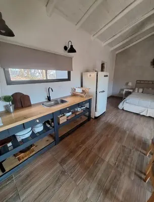 a kitchen with a sink and a refrigerator in a room at Cabañas Posada del Angel in Villa Serranita