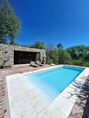 a swimming pool in front of a stone house at Cabañas Posada del Angel in Villa Serranita